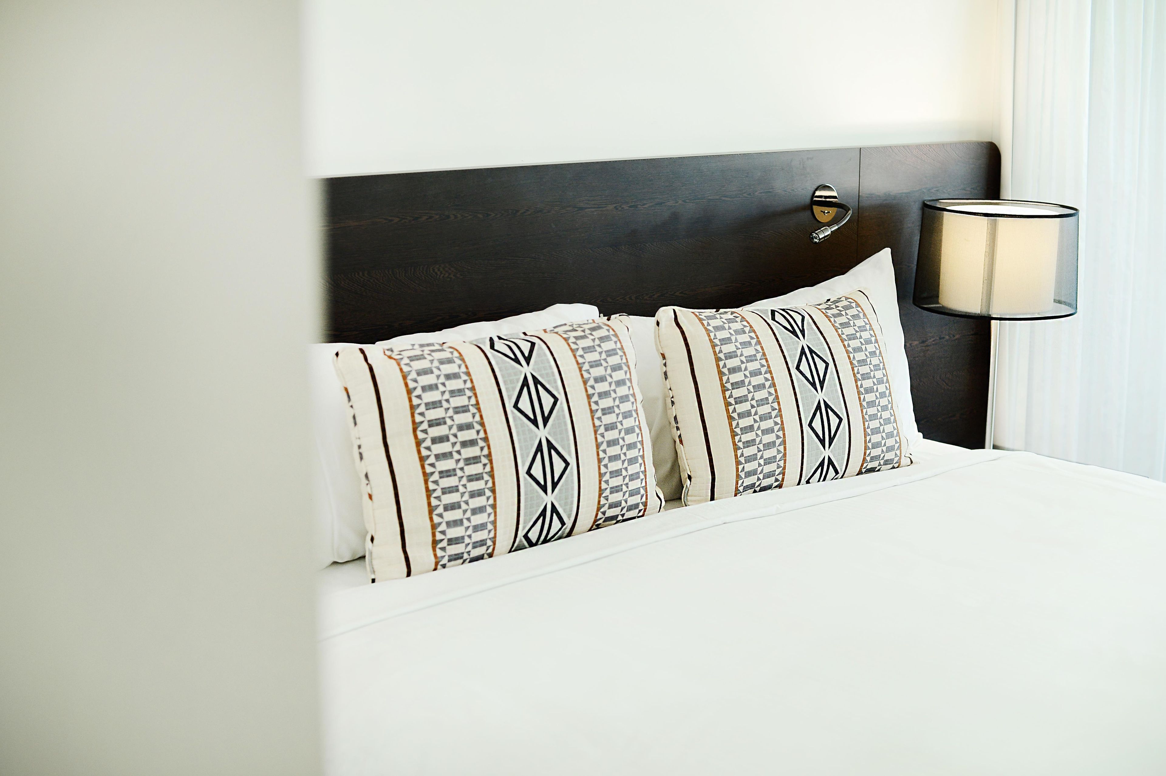 A neatly made bed with patterned pillows and a dark headboard.
