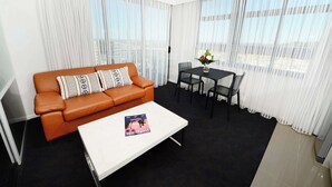 Una sala de estar moderna con un sofá de cuero marrón, una mesa de centro blanca y un comedor con una mesa y sillas negras.