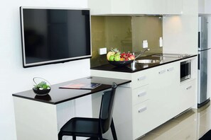 Una cocina moderna con una televisión de pantalla plana, un cuenco de fruta y una silla negra.