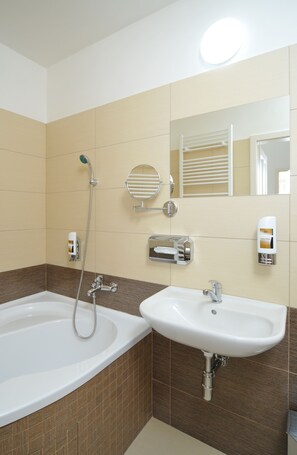 A bathroom with a bathtub, a sink, a mirror, and a towel rack. - Apartment house Anenská (Prague)