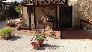 A rustic outdoor seating area with a pergola, stone walls, and potted plants. - Agriturismo Casalicchio (Cammarata)