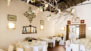 A dining area with multiple tables set for a meal, white chairs, and decorative elements like hanging branches and framed pictures on the walls. - Agriturismo Casalicchio (Cammarata)