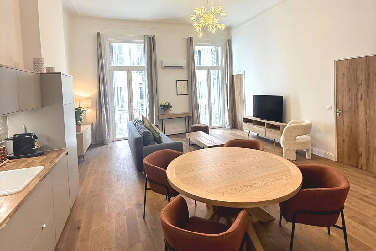 A modern living space with a dining area, kitchen, and seating area.