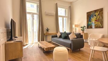 Un salon moderne avec un canapé, un pouf et un coin repas.