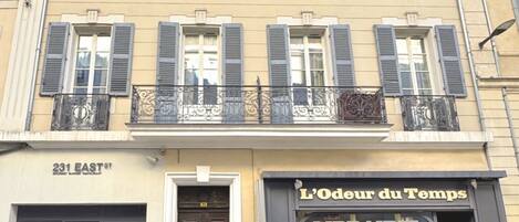 Un edificio con una tienda en la planta baja llamada "L'Odeur du Temps" y un restaurante en el segundo piso llamado "231 EAST ST".