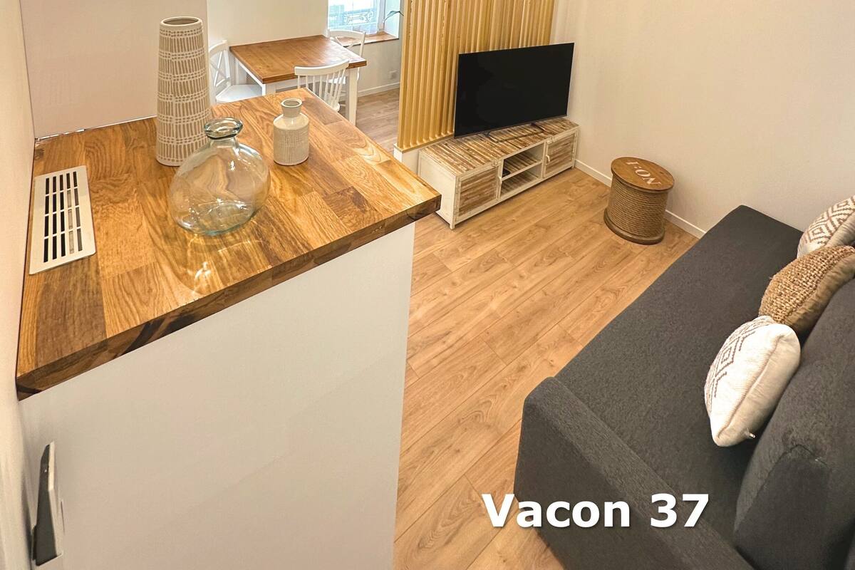 A modern living room with a wooden dining table, a TV, and a sofa.