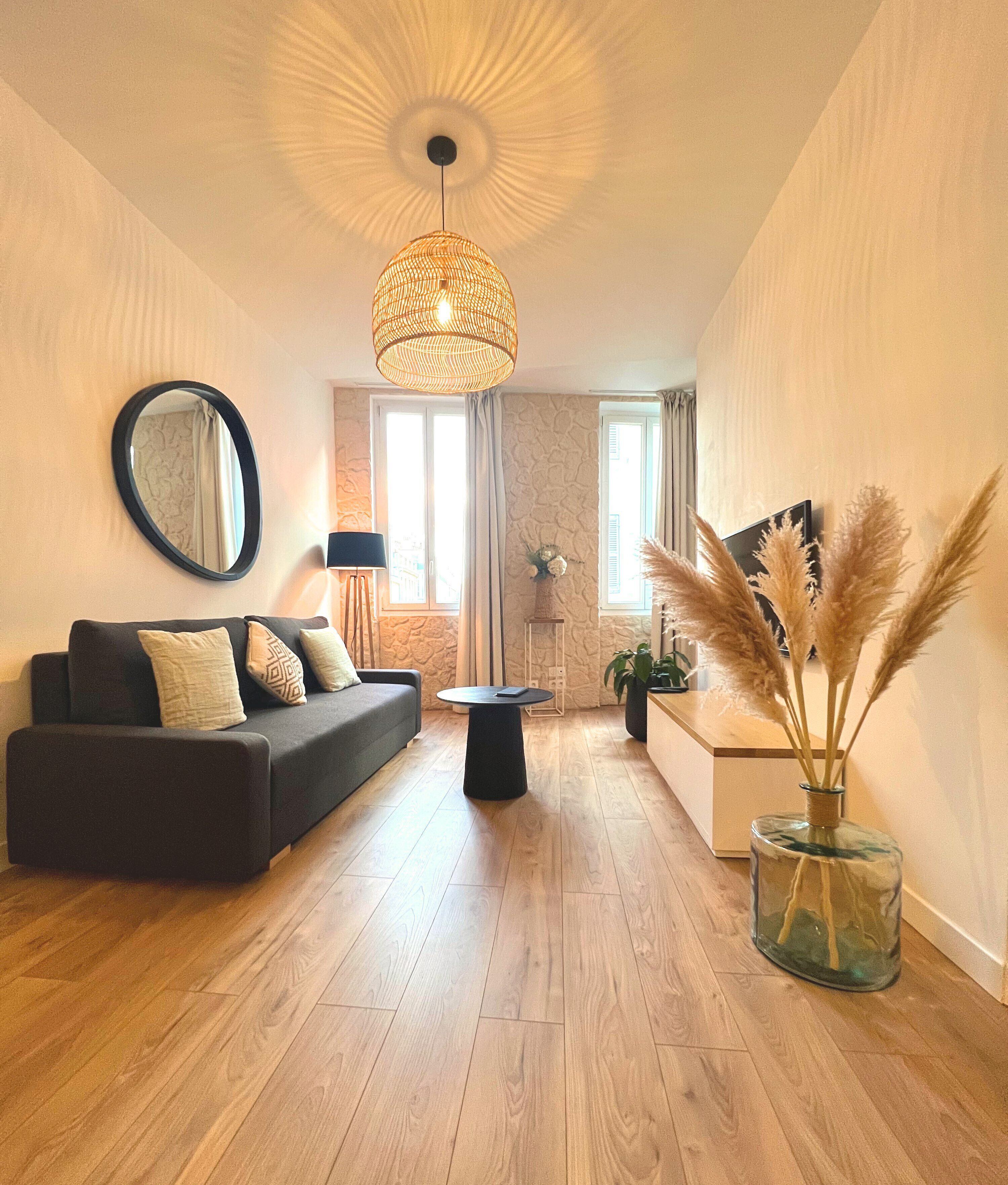 Ein modernes Wohnzimmer mit einem dunklen Sofa, einem runden Couchtisch und einer Pendelleuchte.