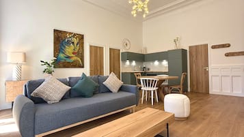 Una sala de estar moderna con un sofá, un banco de madera, una zona de comedor y una cocina al fondo.
