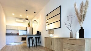 A modern kitchen with a central island, bar stools, pendant lighting, and a large mirror. - Les Appartements du Vieux-Port (Marseille)