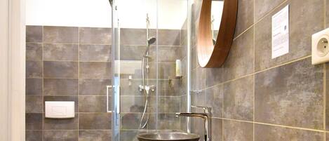 A modern bathroom with a wooden vanity, a large mirror, and a glass-enclosed shower.