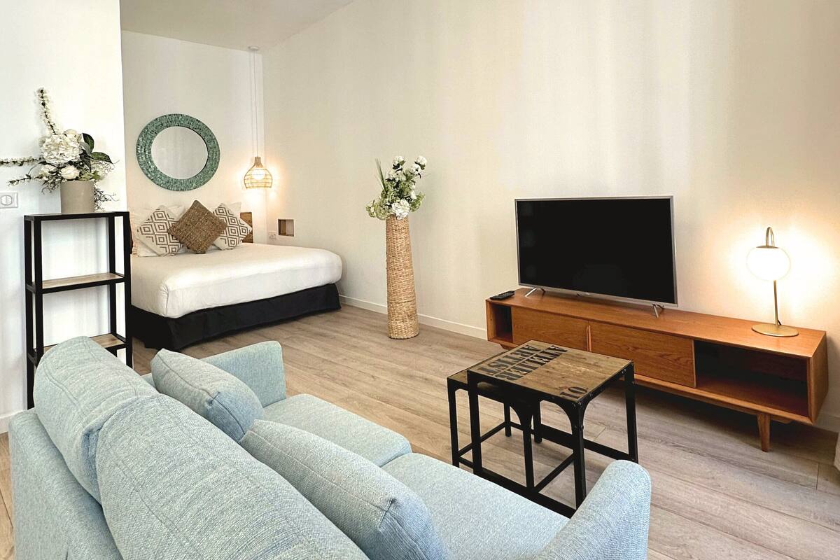 A modern living room with a sofa, a TV, a wooden cabinet, and a hanging light fixture.