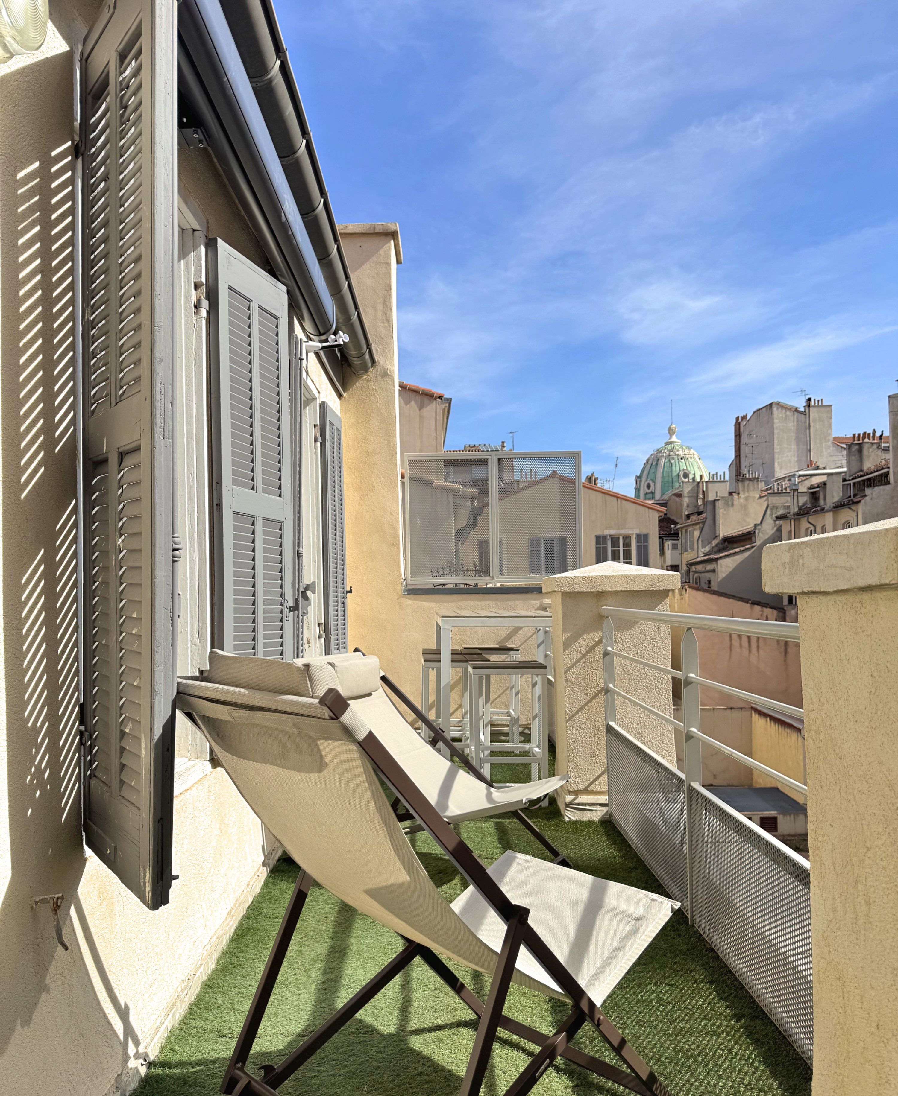 Una terraza en la azotea con toldo retráctil, una mesa pequeña y una silla.