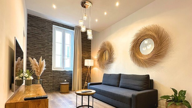A modern living room with a wooden coffee table, a grey sofa, and a round mirror on the wall. - Les Appartements du Vieux-Port (Marseille)