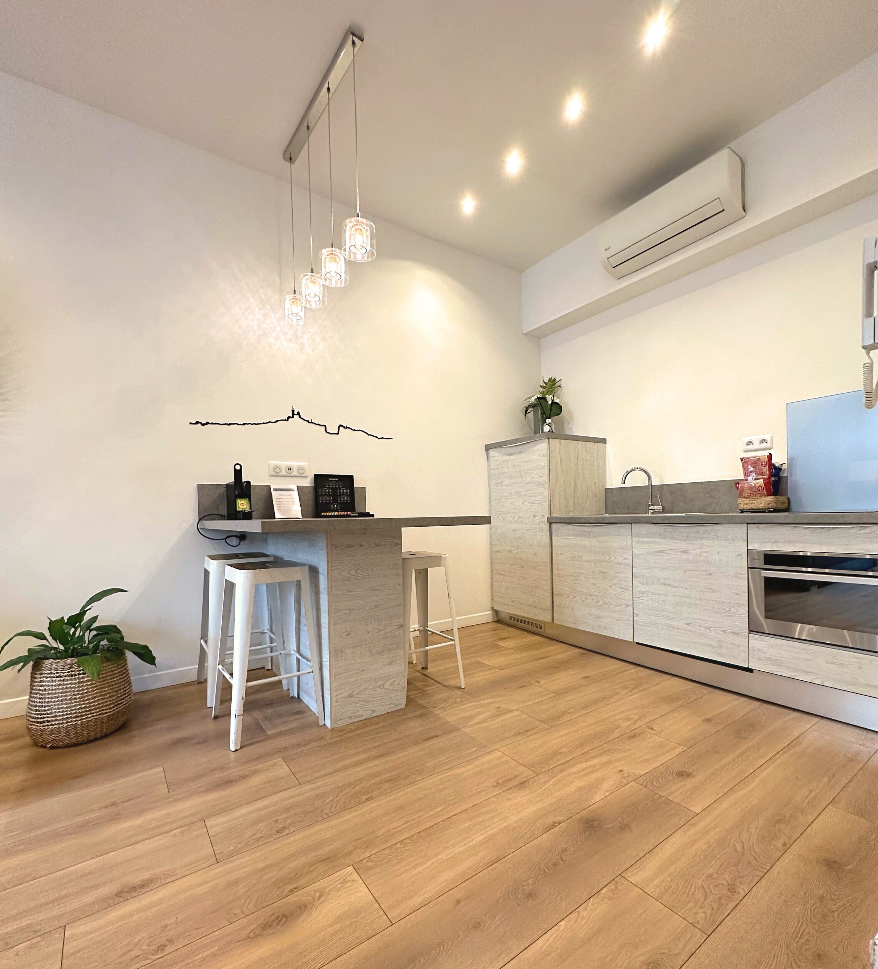 A modern kitchen with a central island, bar stools, a built-in oven, and pendant lighting.