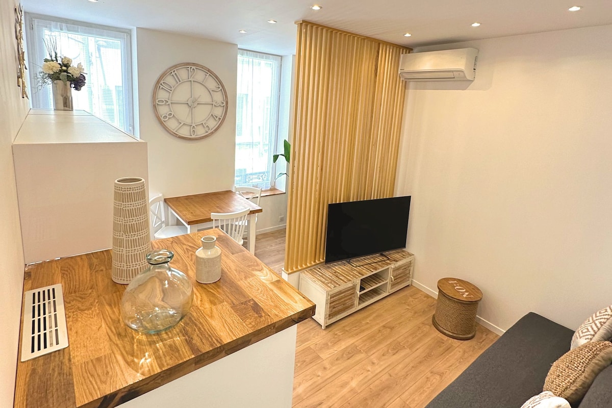 A modern living room with a wooden dining table, a TV, and a sofa.
