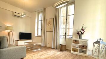 A spacious living room with a grey sofa, a flat-screen TV, a wooden coffee table, and a decorative lantern.