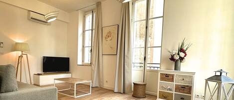 A spacious living room with a grey sofa, a flat-screen TV, a wooden coffee table, and a decorative lantern.