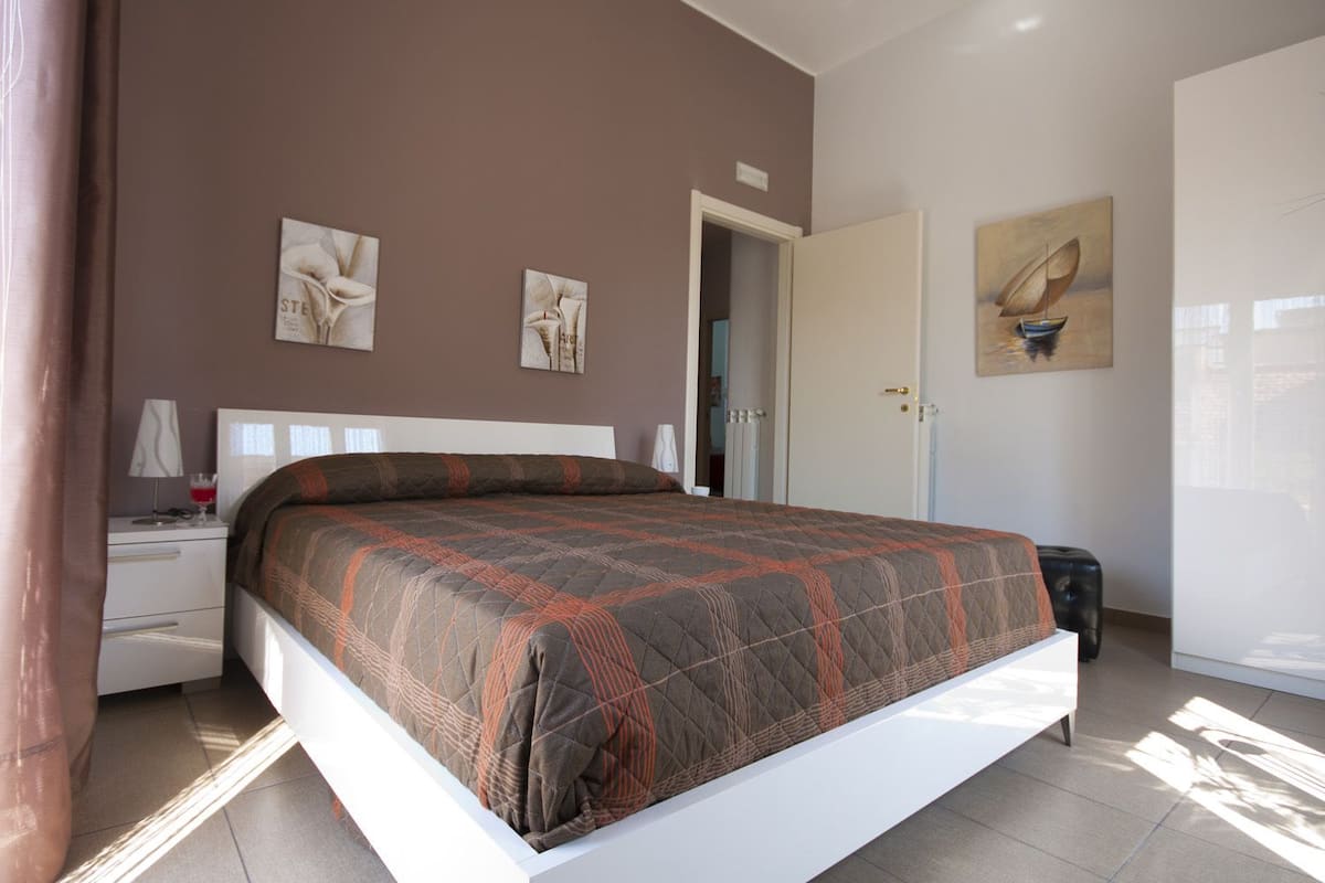 A bedroom with a bed, a nightstand, a lamp, and artwork on the walls.