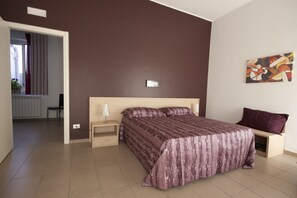 A modern bedroom with a large bed, a bedside table, a chair, and a painting on the wall.