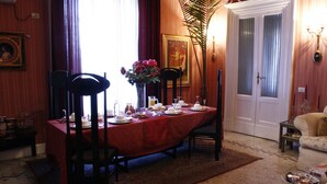 Ein Esszimmer mit Tisch für vier Personen, Stühlen, einer Blumenvase und einem gerahmten Bild an der Wand.
