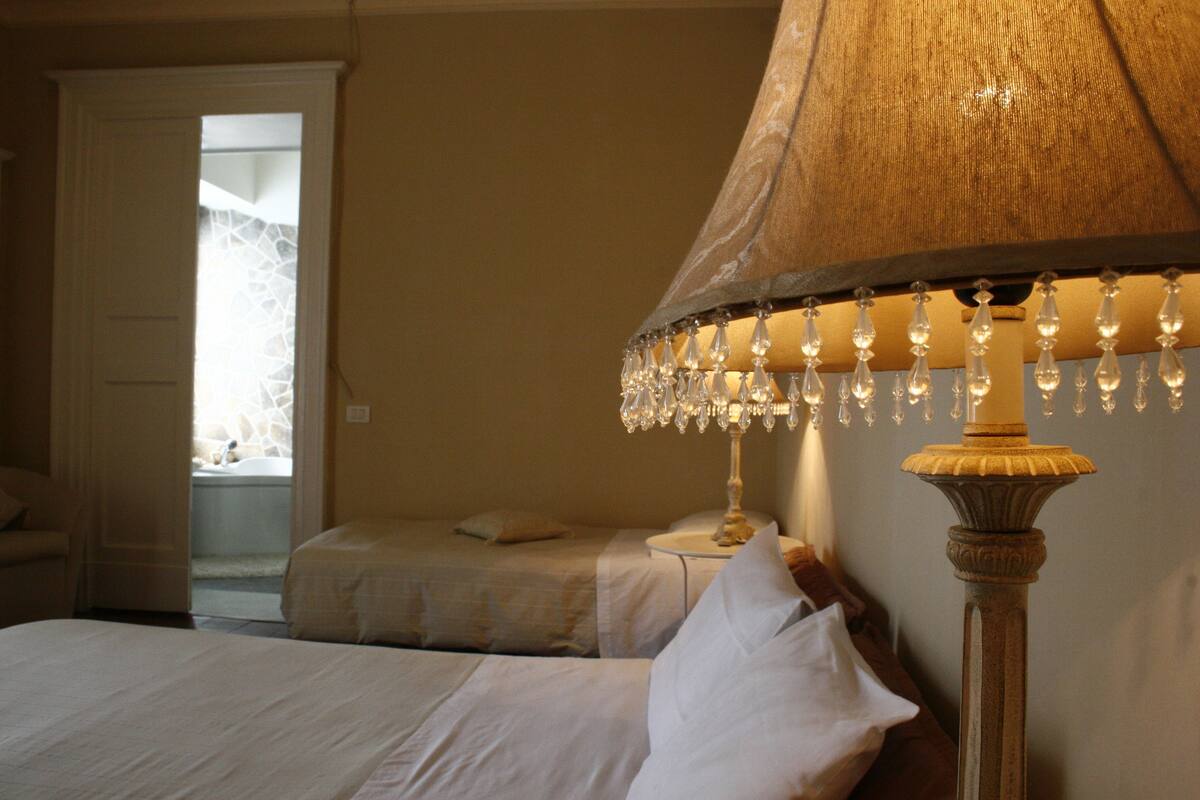 Een slaapkamer met twee bedden, een nachtkastje en een lamp met kristaldecoraties.