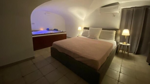 Ein Schlafzimmer mit einem großen Bett, einem Nachttisch, einer Lampe und einer Klimaanlage an der Wand.