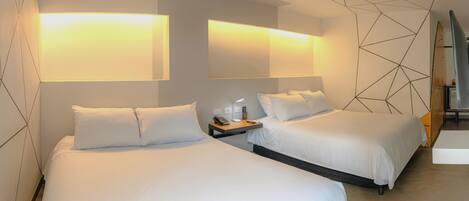 Ein Hotelzimmer mit zwei Betten, einem Nachttisch mit Lampe und geometrischer Wandgestaltung.