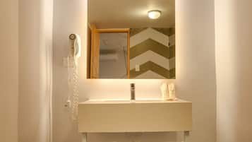 A bathroom with a white sink, a mirror, and two towels hanging on hooks.