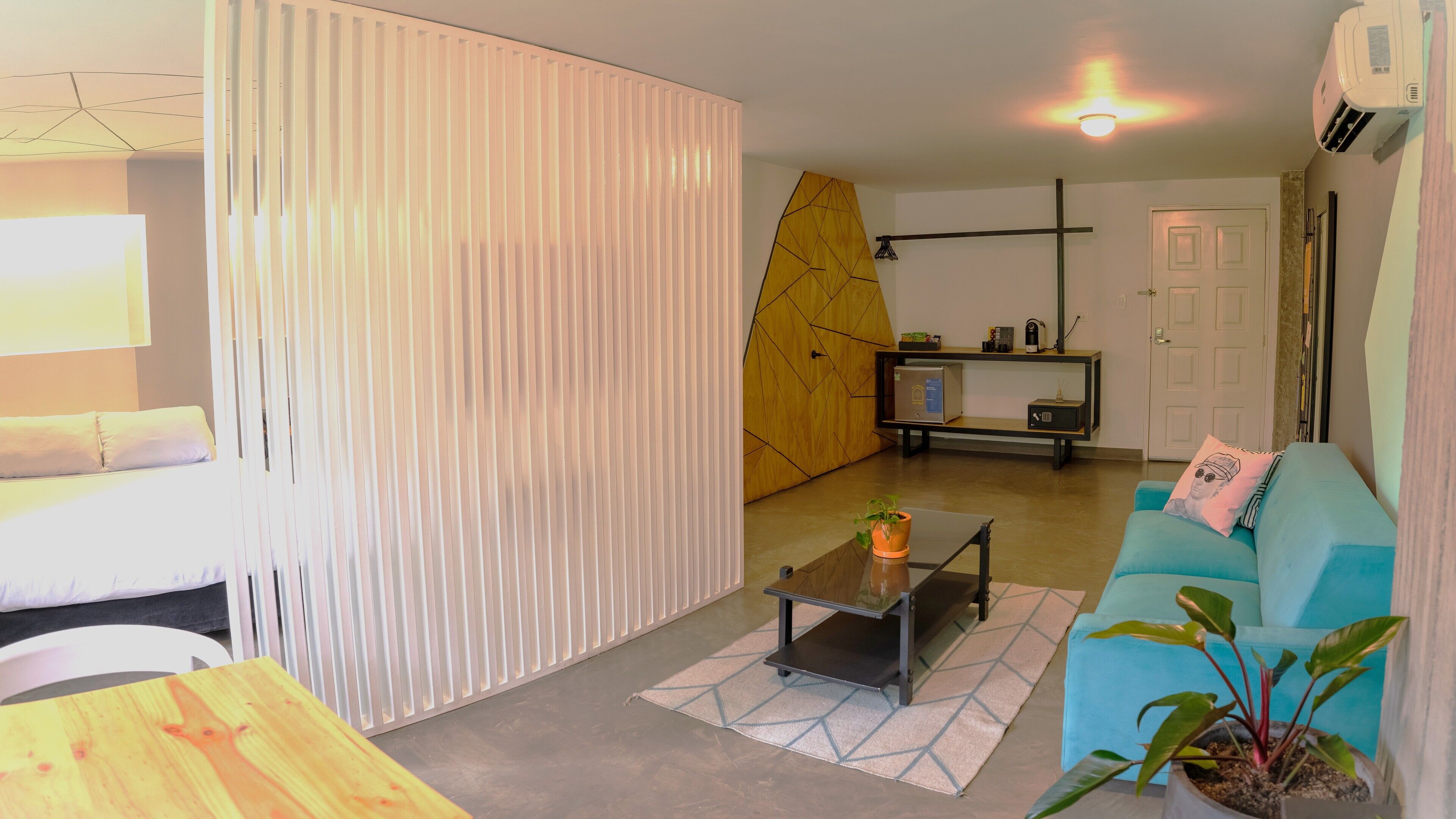 Una sala de estar moderna con un sofá, una mesa de centro, una planta en maceta y una alfombra con motivos geométricos.