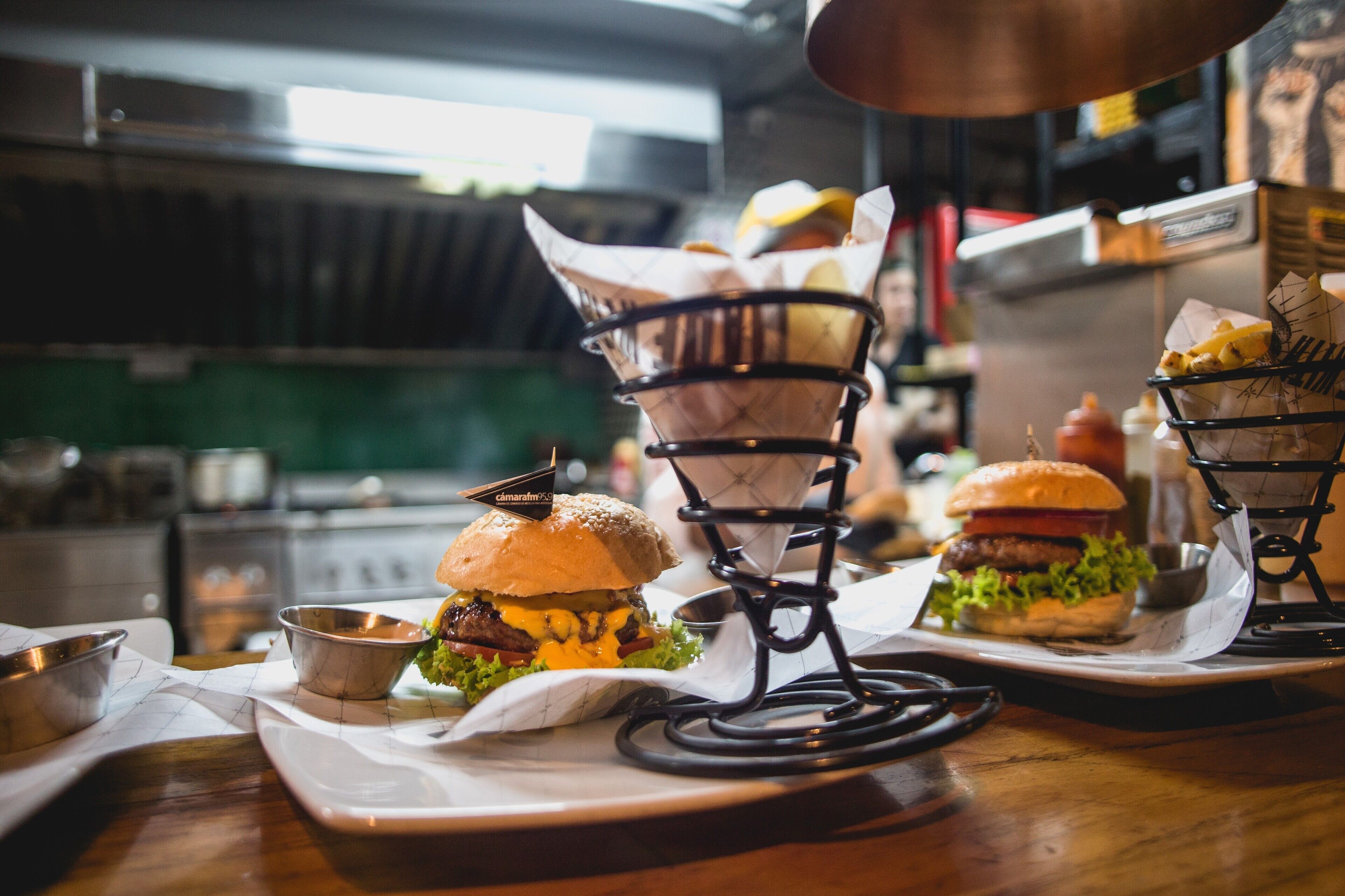 En restaurantscene med en burger på en bakke, en kurv med pommes frites, og en burger på et stativ.