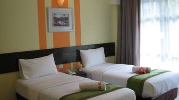 A hotel room with two beds, a nightstand, a framed picture, and a window with curtains.
