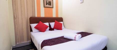A neatly made bed with white and red bedding, a brown headboard, and a framed picture on the wall.