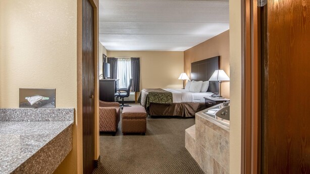 Ein Hotelzimmer mit Bett, Schreibtisch, Stuhl, kleinem Tisch und Badebereich.