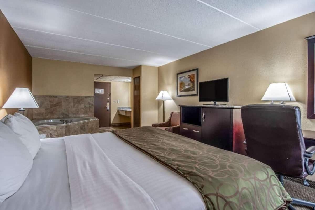 A hotel room with a bed, a desk, a chair, a television, and a bathroom.