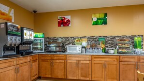 Eine Hotelküche mit Kaffeemaschine, Mikrowelle, Toaster und einer Obstauslage.