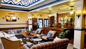 A spacious lobby with a high ceiling, a bar area, and comfortable seating. - Monte Villa Hotel (Monte Vista)