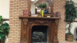 A brick fireplace with a mirror above it, flanked by books and a potted plant. - Monte Villa Hotel (Monte Vista)