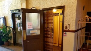 A hotel entrance with a closed door, a staircase, and a sign indicating a coffee shop. - Monte Villa Hotel (Monte Vista)
