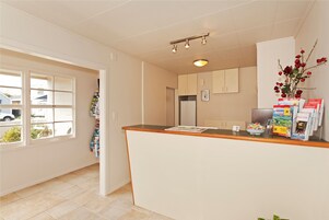 A kitchen with a wooden countertop, a refrigerator, and a window with a view of the outside.