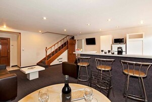 A modern kitchen with a bar area, a staircase, and a seating area with a round table and chairs.