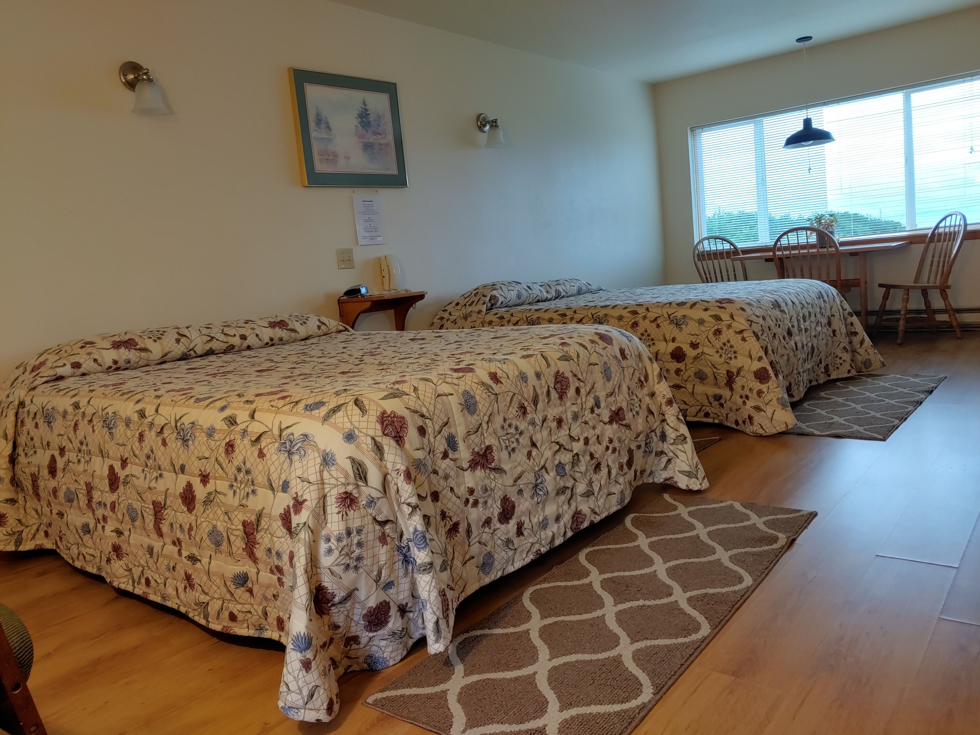 A room with two beds, a desk, and a chair.