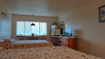 Une chambre avec deux lits, un bureau avec un ordinateur, une chaise et une fenêtre avec des stores.