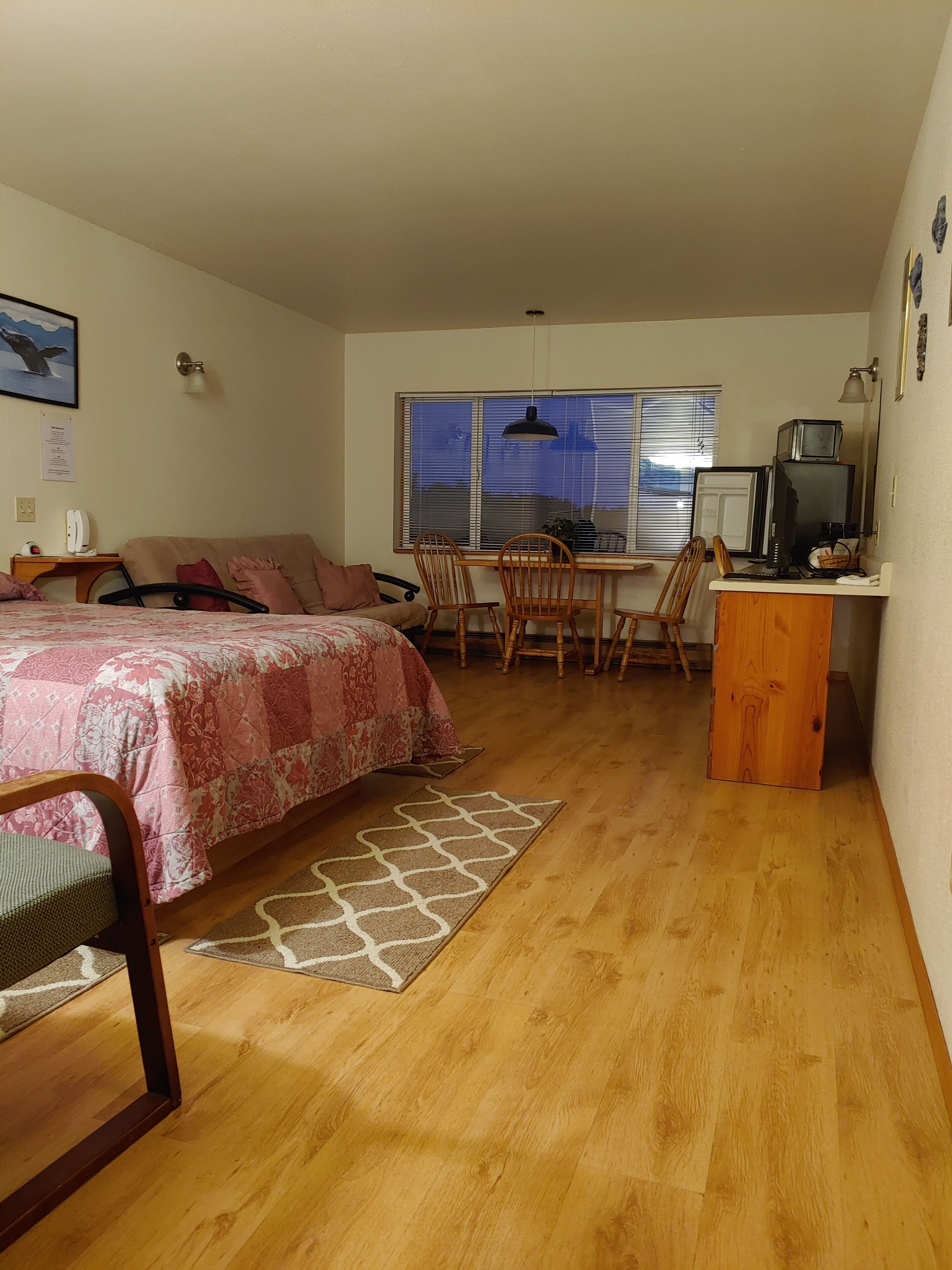 A bedroom with a bed, a desk, and a dining area.