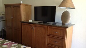Un dormitorio con un armario de madera, un televisor y una lámpara.