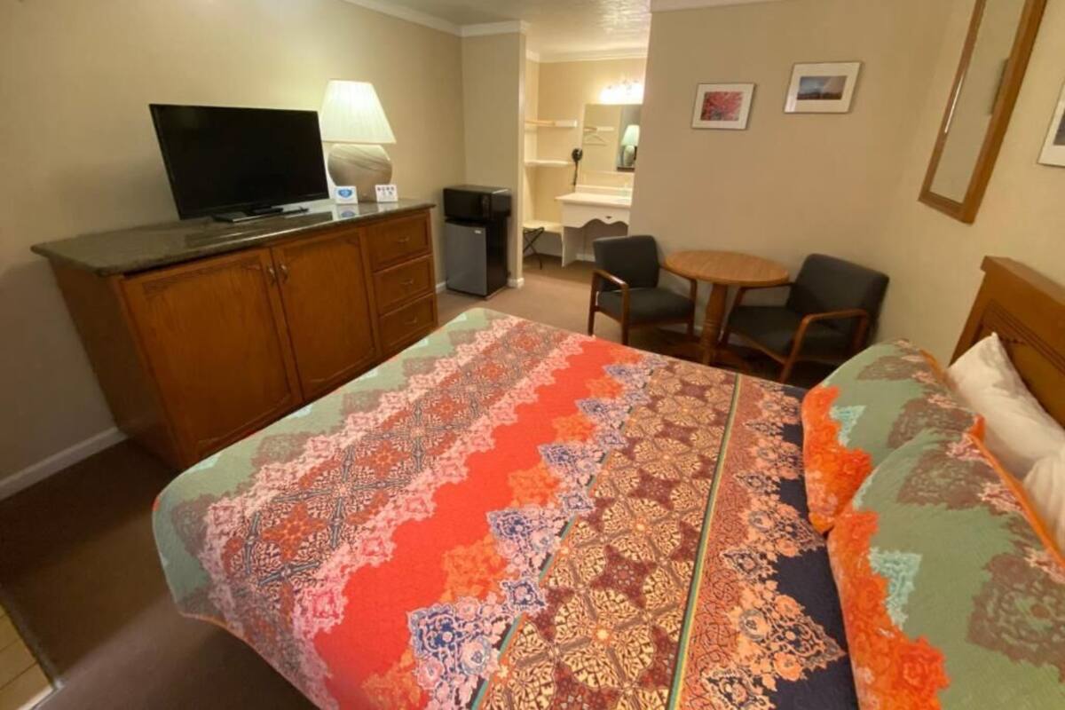 Hotellihuone, jossa on sänky, työpöytä, tuoli, televisio ja lamppu.
