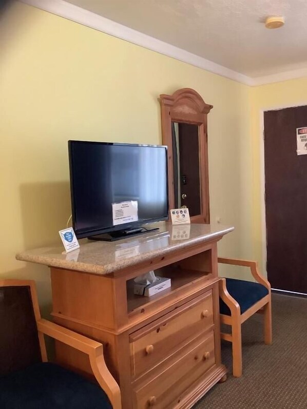 A wooden desk with a television, a small sign, and a mirror. - Independence Courthouse Motel (Independence)