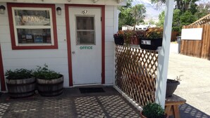 Un edificio con un letrero que indica 'VACANCY', un letrero que dice 'OFFICE' y una puerta con el número '157'. Hay plantas en macetas afuera.