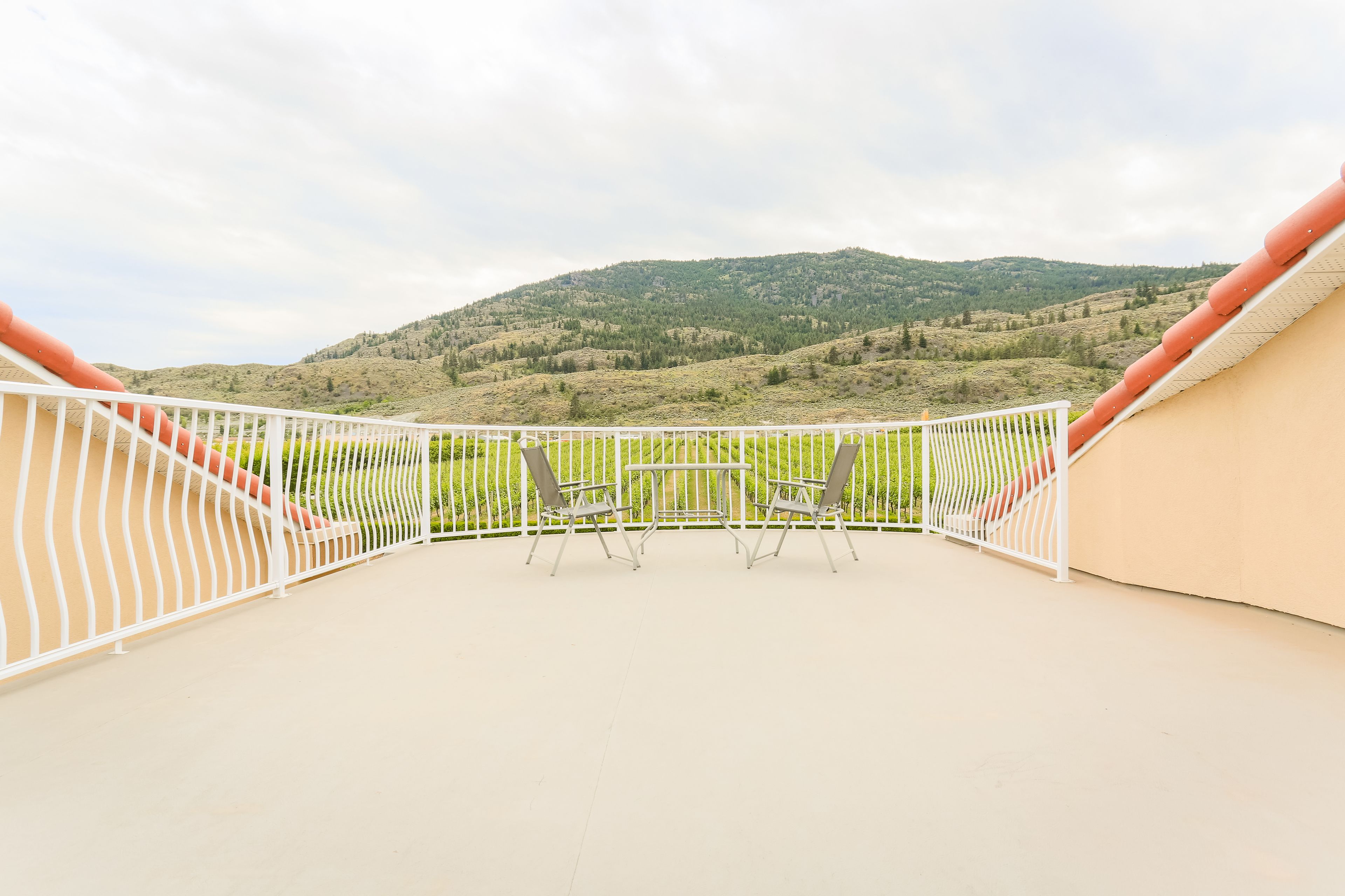 Un balcon avec une balustrade blanche, deux chaises et une table.