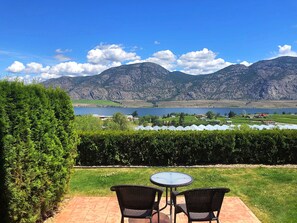 A patio with two chairs and a table overlooking a lake and mountains. - Shiraz Villa (Osoyoos)