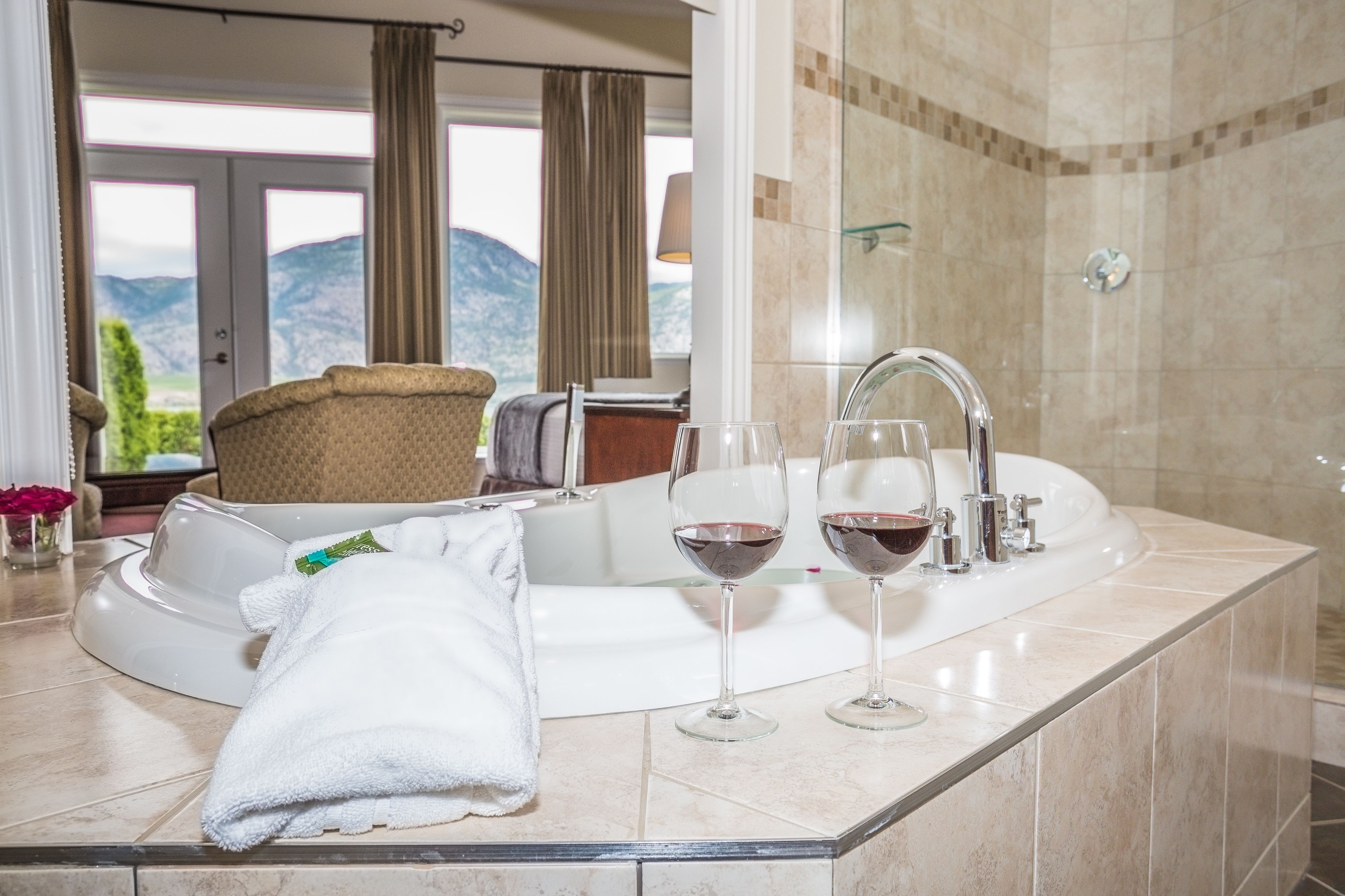 A modern bathroom with a bathtub, two wine glasses, and a towel.